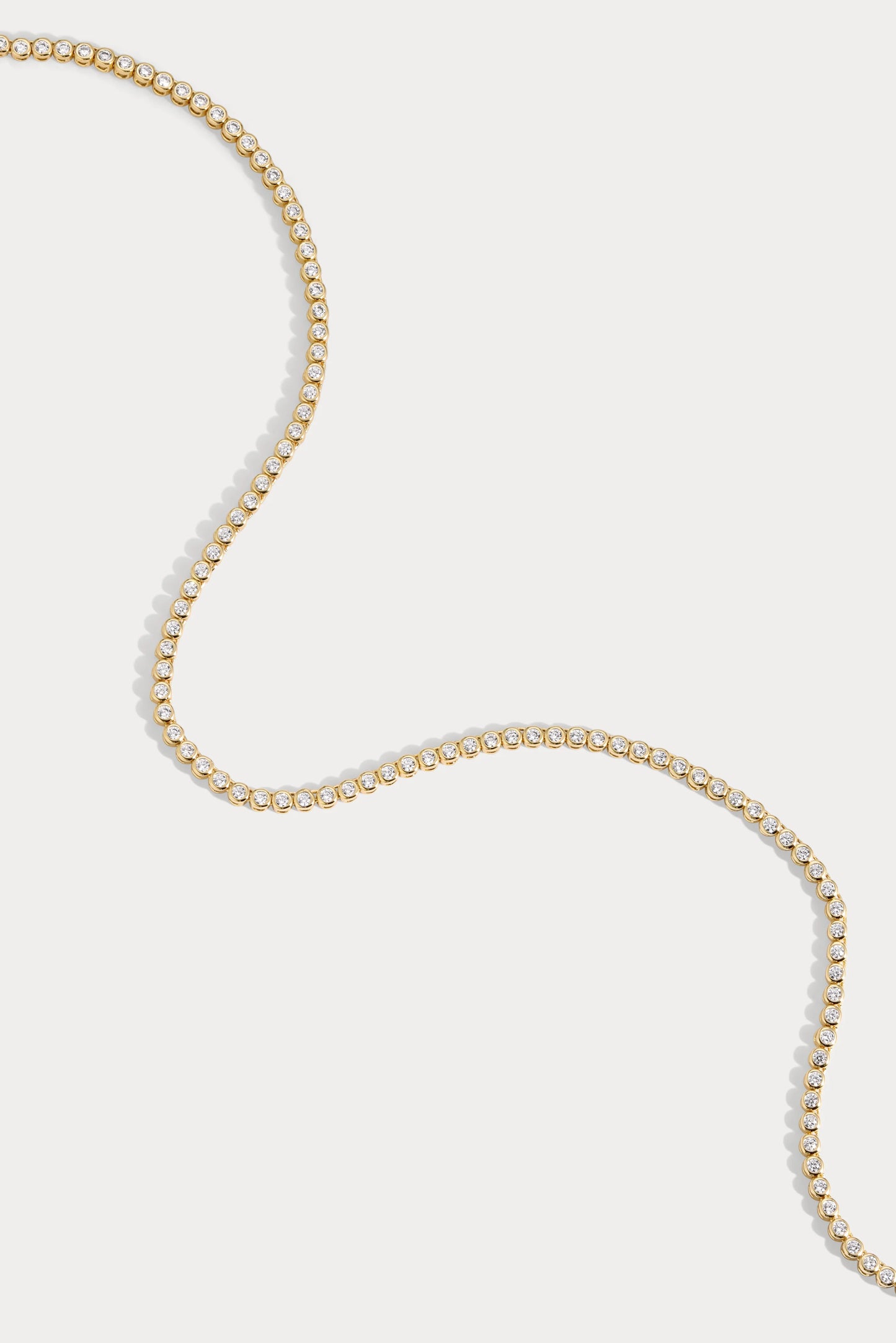 Close up of Charm City Link's Classic Tennis Necklace, a round bezel set in 14k gold plated brass with CZ stones around. You can see different angles of the diamonds.