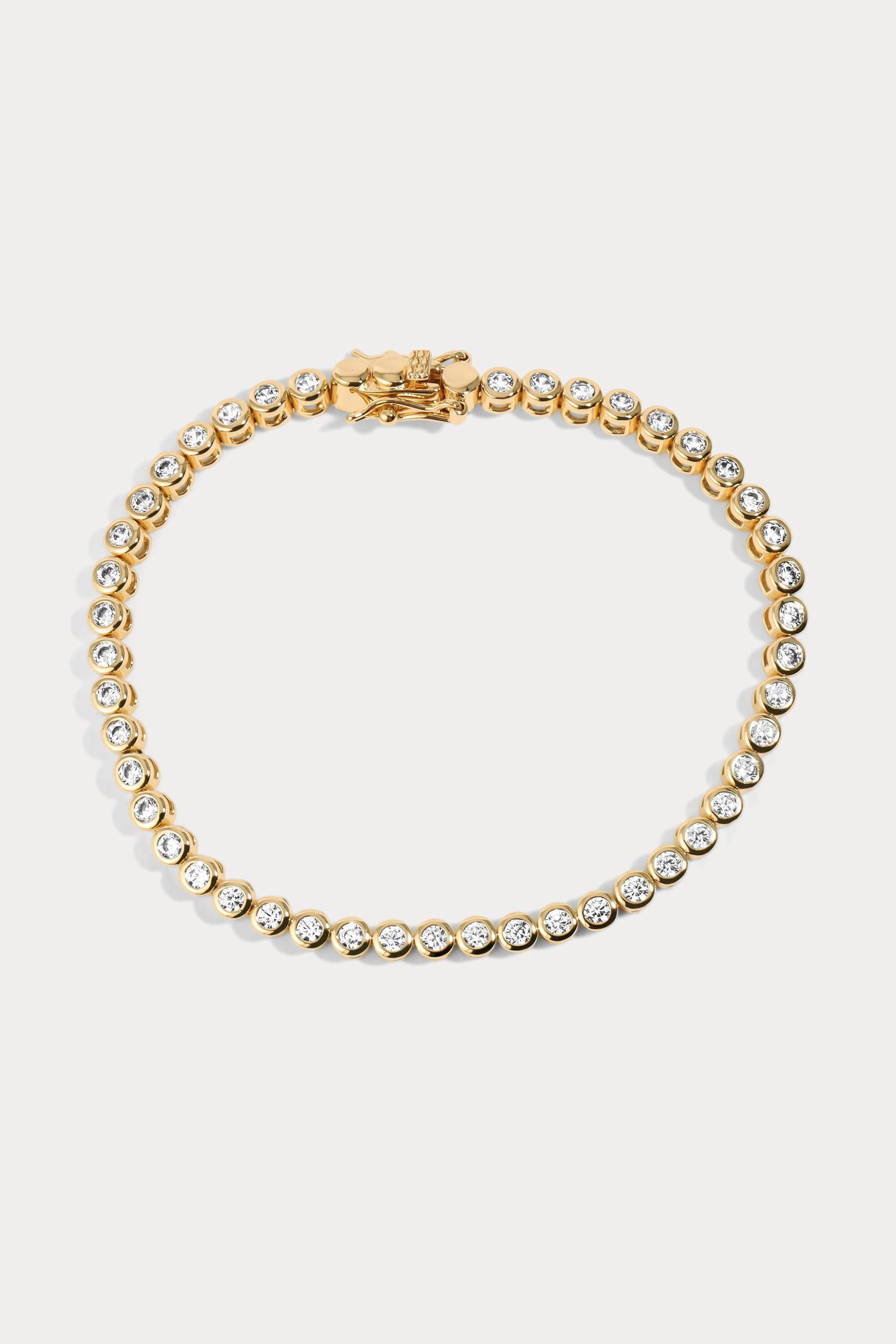 Flatlay of a gold-plated brass tennis bracelet by Charm City Links, with 2mm cubic zirconia diamonds around it.