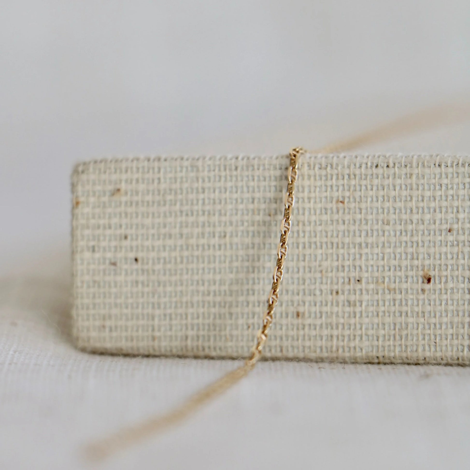 Twisted 14k gold chain used to make permanent jewelry including bracelets and necklaces at Charm City Links, on a woven jewelry holder.