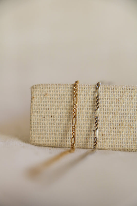 Two permanent jewelry links with three small ovals and one large oval link in a pattern, called the Figaro link, and shown with gold-filled on left and sterling silver on right.