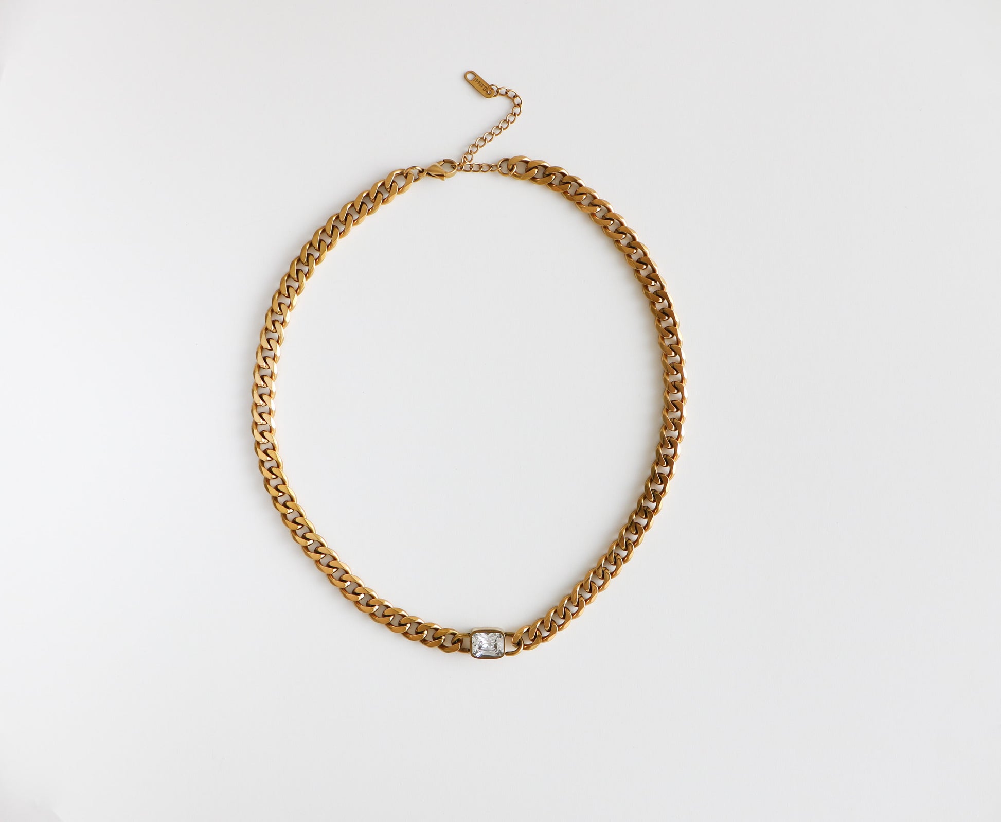 Chunky gold-filled chain necklace with a dainty diamond at the bottom, laying flat on a white background.