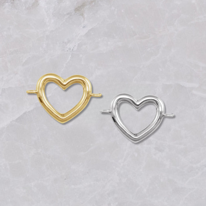 Heart-shaped 14k yellow gold and sterling silver connectors for permanent bracelets, shown on a marble background.