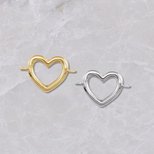 Heart-shaped 14k yellow gold and sterling silver connectors for permanent bracelets, shown on a marble background.
