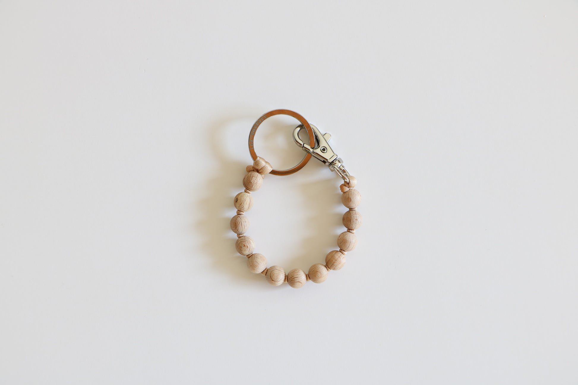 Natural wooden beaded keychain held together with a metal clasp on a light background. 