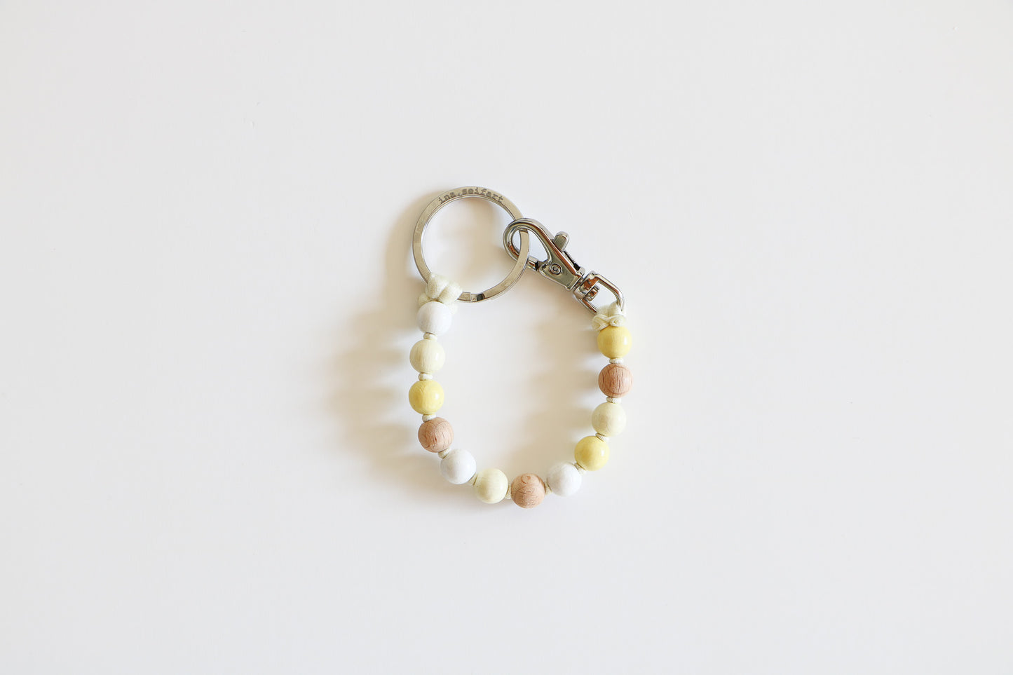 Small wooden beaded keychain meant to hold keys on a white background, shown in the Neutral Mix option with natural, white, and light yellow beads.