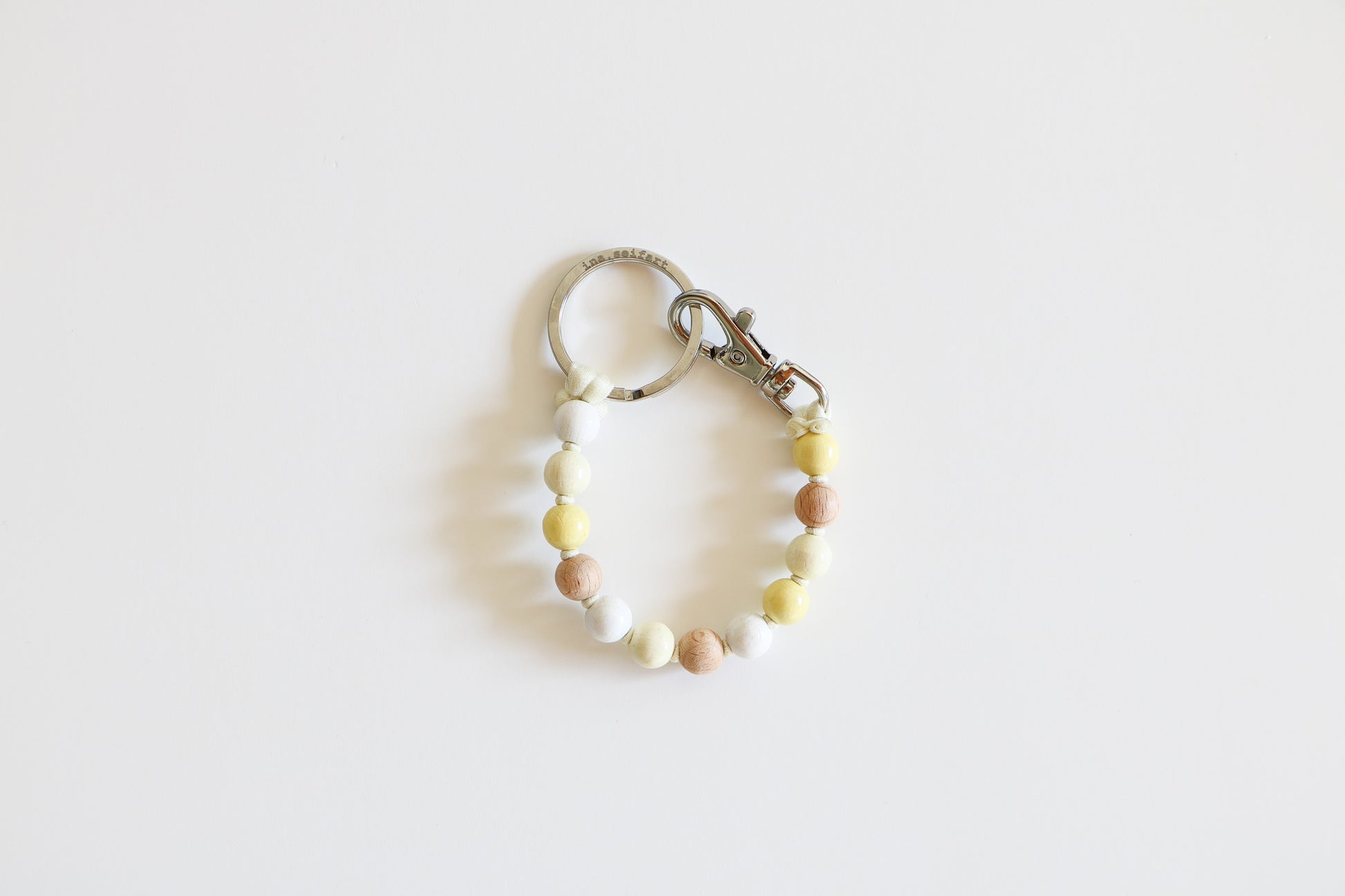 Small wooden beaded keychain meant to hold keys on a white background, shown in the Neutral Mix option with natural, white, and light yellow beads.