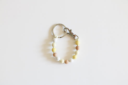 Small wooden beaded keychain meant to hold keys on a white background, shown in the Neutral Mix option with natural, white, and light yellow beads.