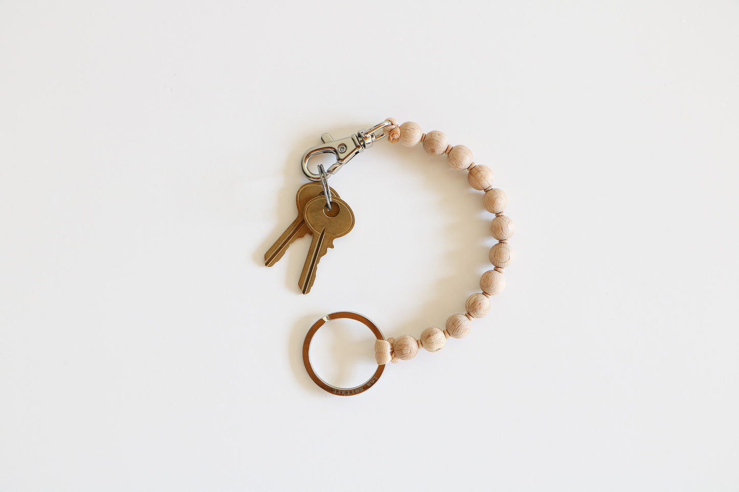 Small natural wood beaded keychain on a light white background, with a metal clasp holding two small brass keys. 