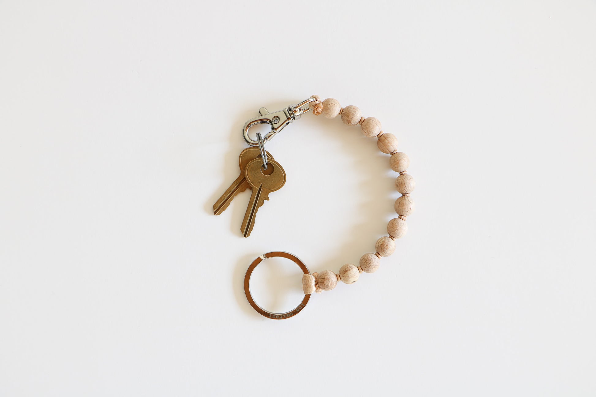 Small natural wood beaded keychain on a light white background, with a metal clasp holding two small brass keys. 