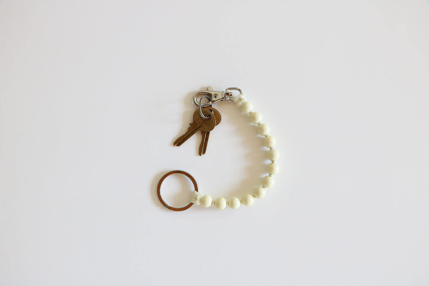 Beaded keychain with a metal clasp holding two small brass keys. Beads are shown in the 'Opal' option of a light white. 