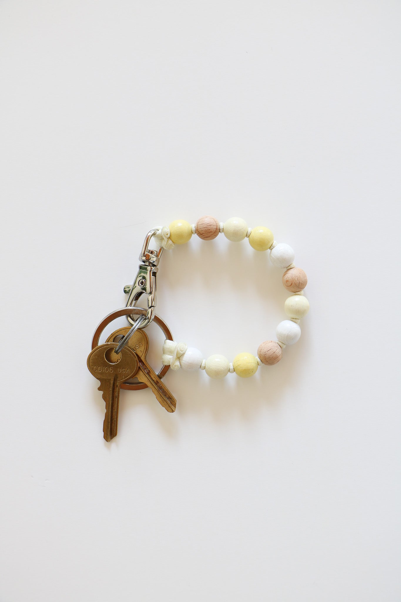 Natural wood keychain in the style 'White Mix', which includes wood beads in natural, white, off-white, and pale yellow, holding two small keys.