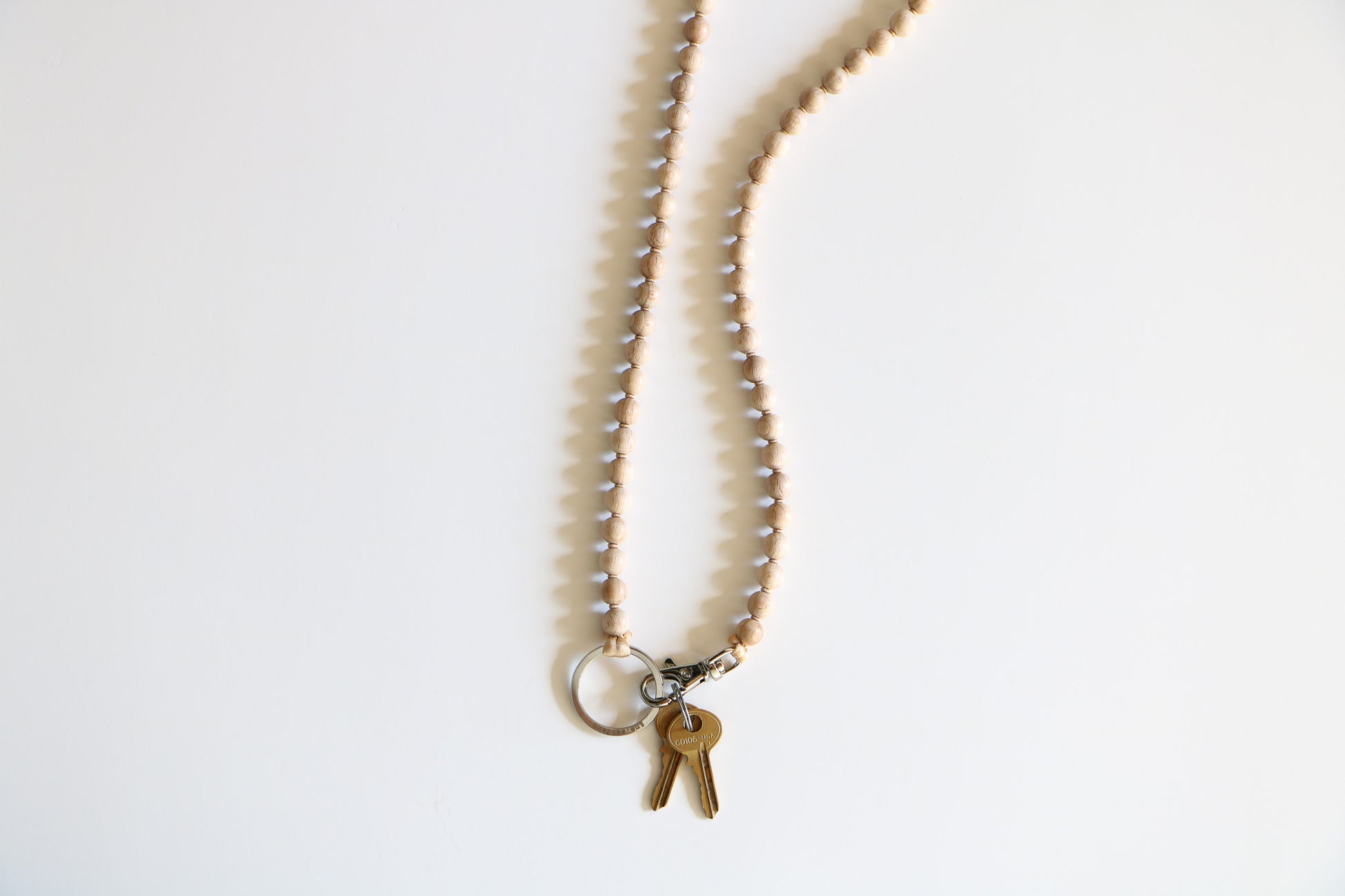 Natural wooden beaded keychain laying flat on a white background, with two small gold keys attached by a metal clasp.
