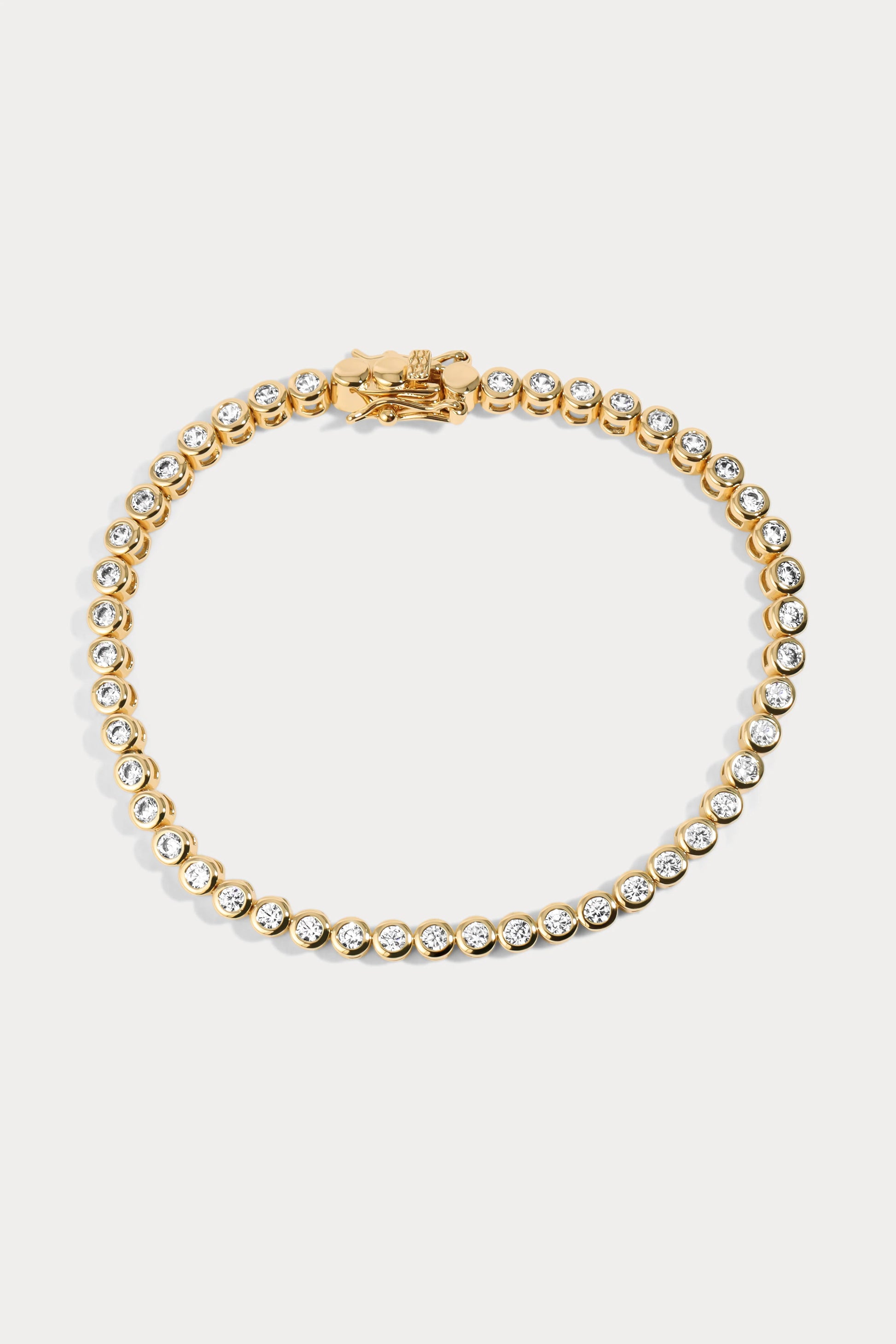 Flatlay of a gold-plated brass tennis bracelet by Charm City Links, with 2mm cubic zirconia diamonds around it.